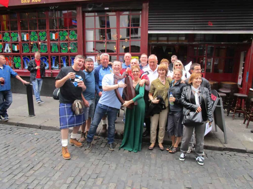 Temple Bar Dubliners in Ireland crowd surrounds Harper Esther Underhay with her Irish Harp for a picture